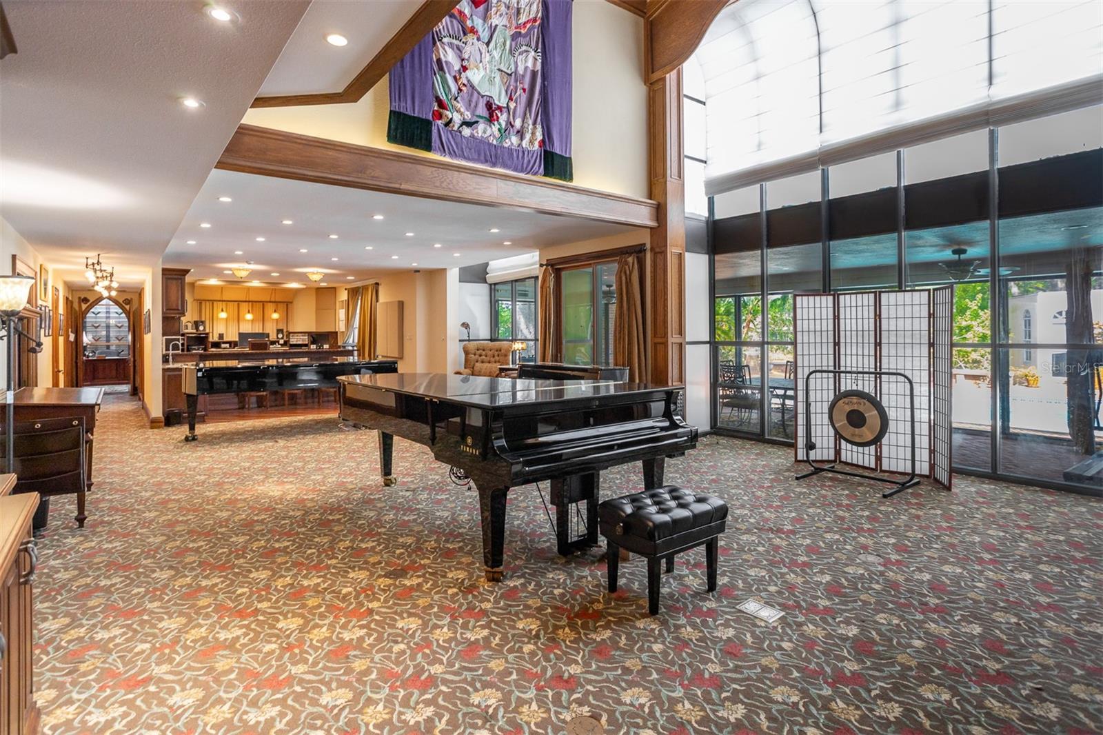 The grand room, currently a vibrant music space offers boundless vesatility, ideal for family gatherings, entertainment or simply savoring the serenity of the backyard sanctuary.