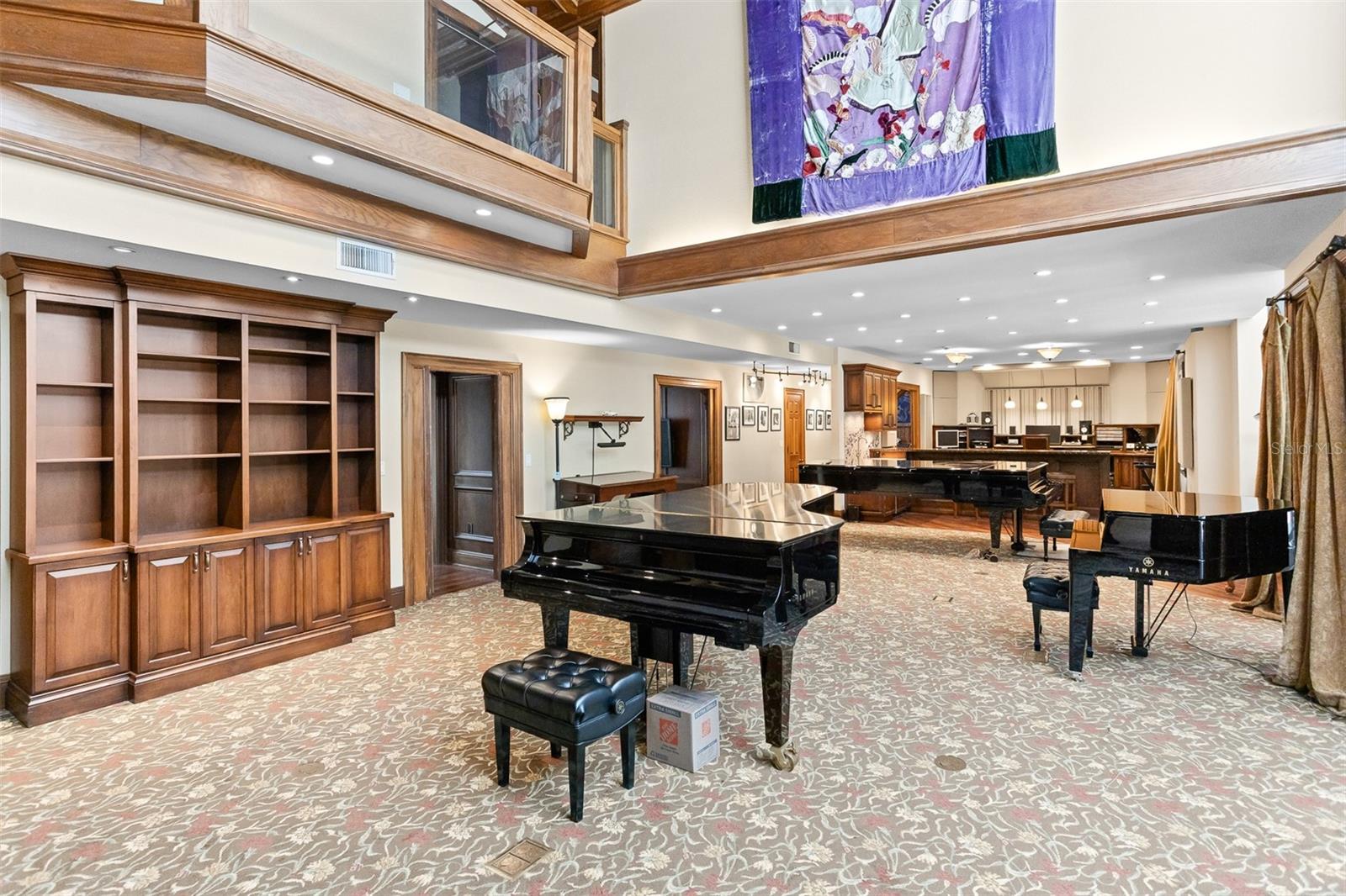 This expansive grand room is a true centerpiece, with soaring vaulted ceilings that create a sense of openness and drama. From here you have a seamless view of the recording studio at one end while the side opens up to the serene pool area.
