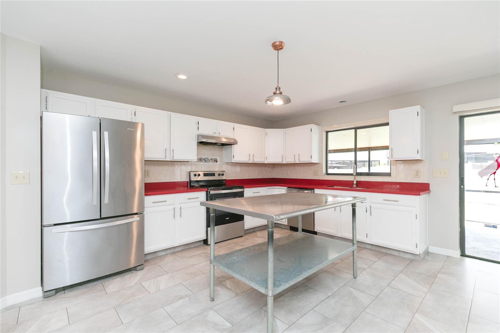 Open kitchen with chefs food prep table, tiled backsplash with bright counter tops that can be painted any color to match your decorating ideas