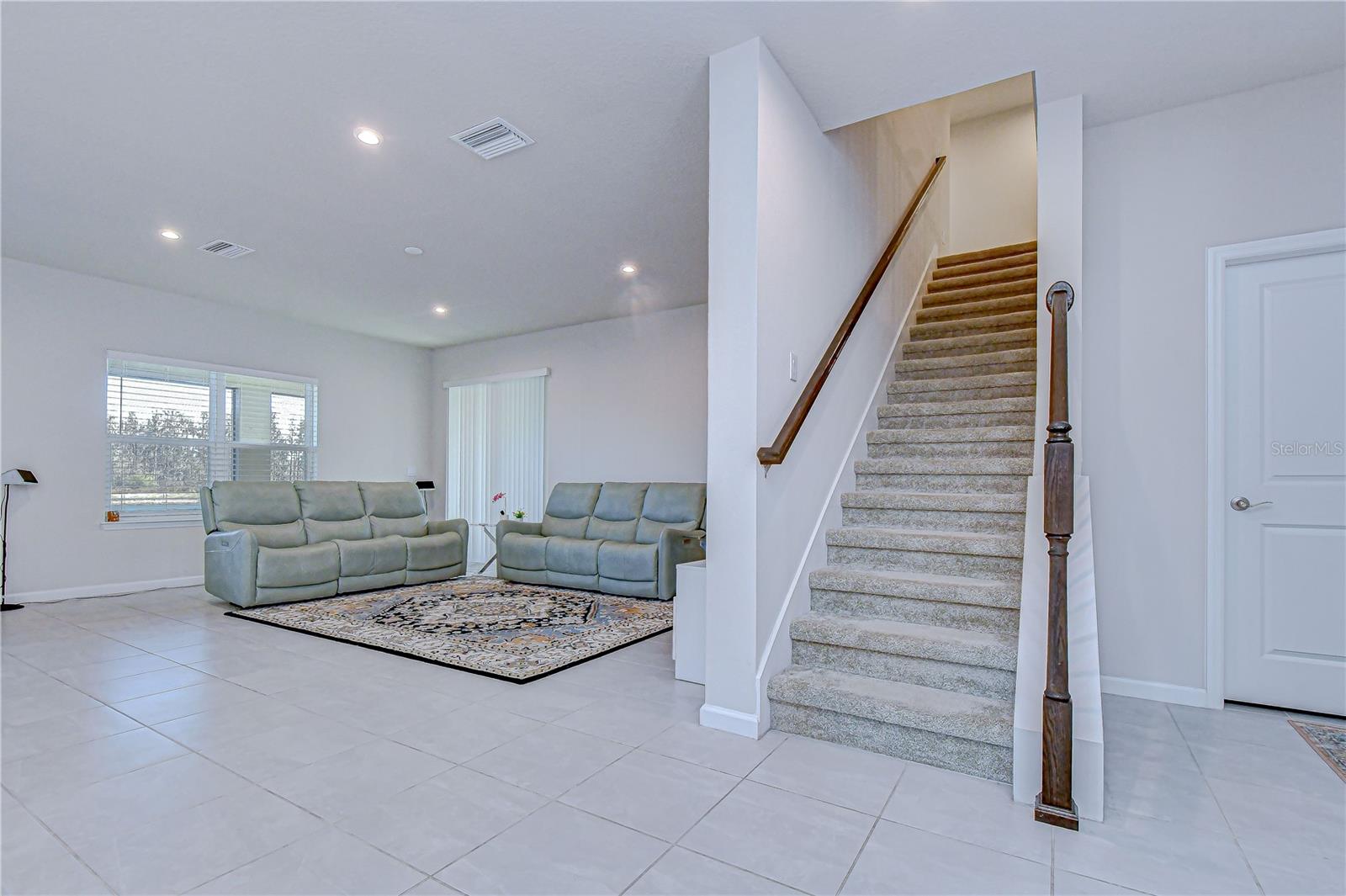 Seamless flow from foyer to living area with staircase view.