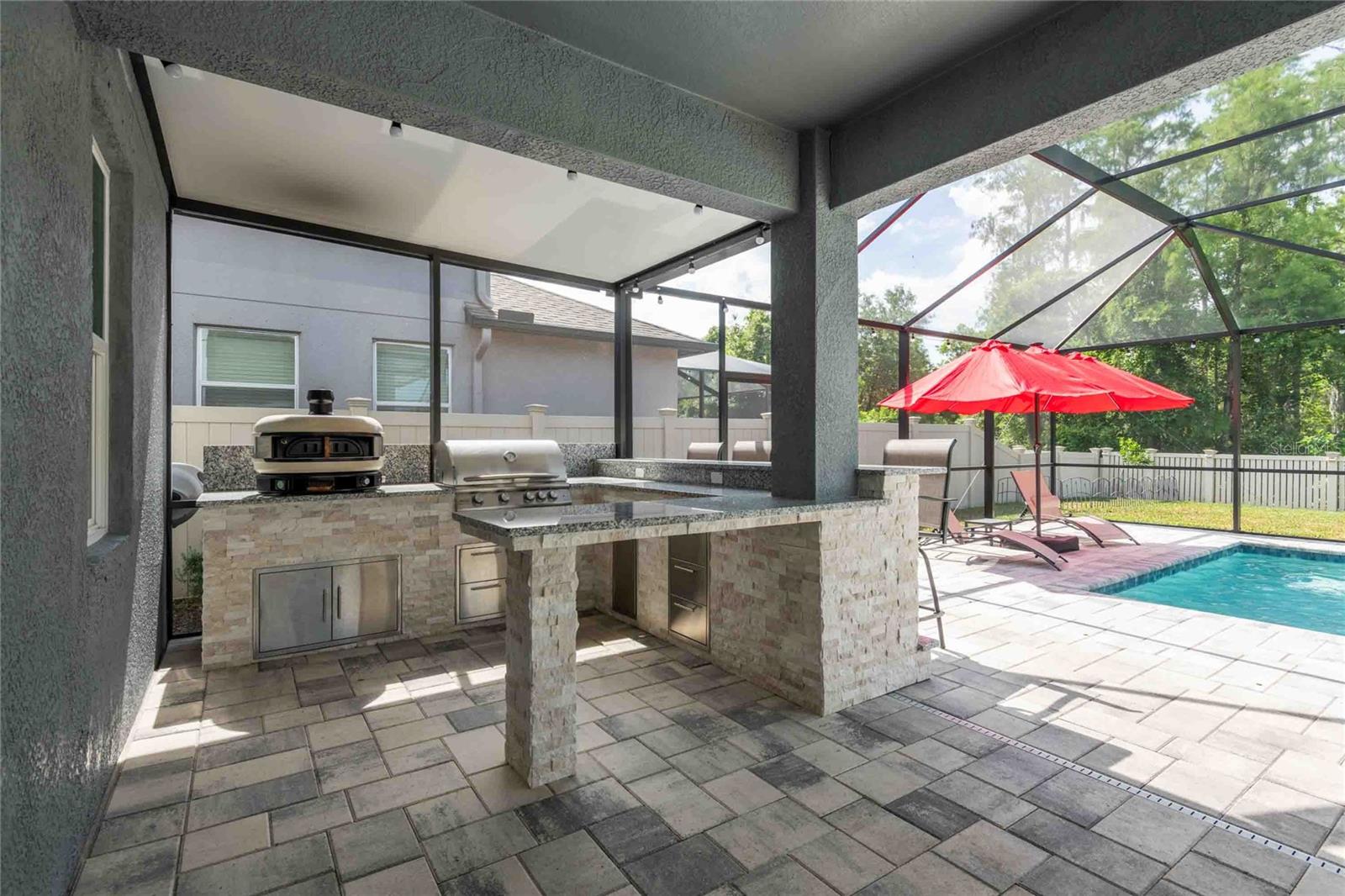 Outdoor kitchen with propane pizza oven and grill with storage drawers.