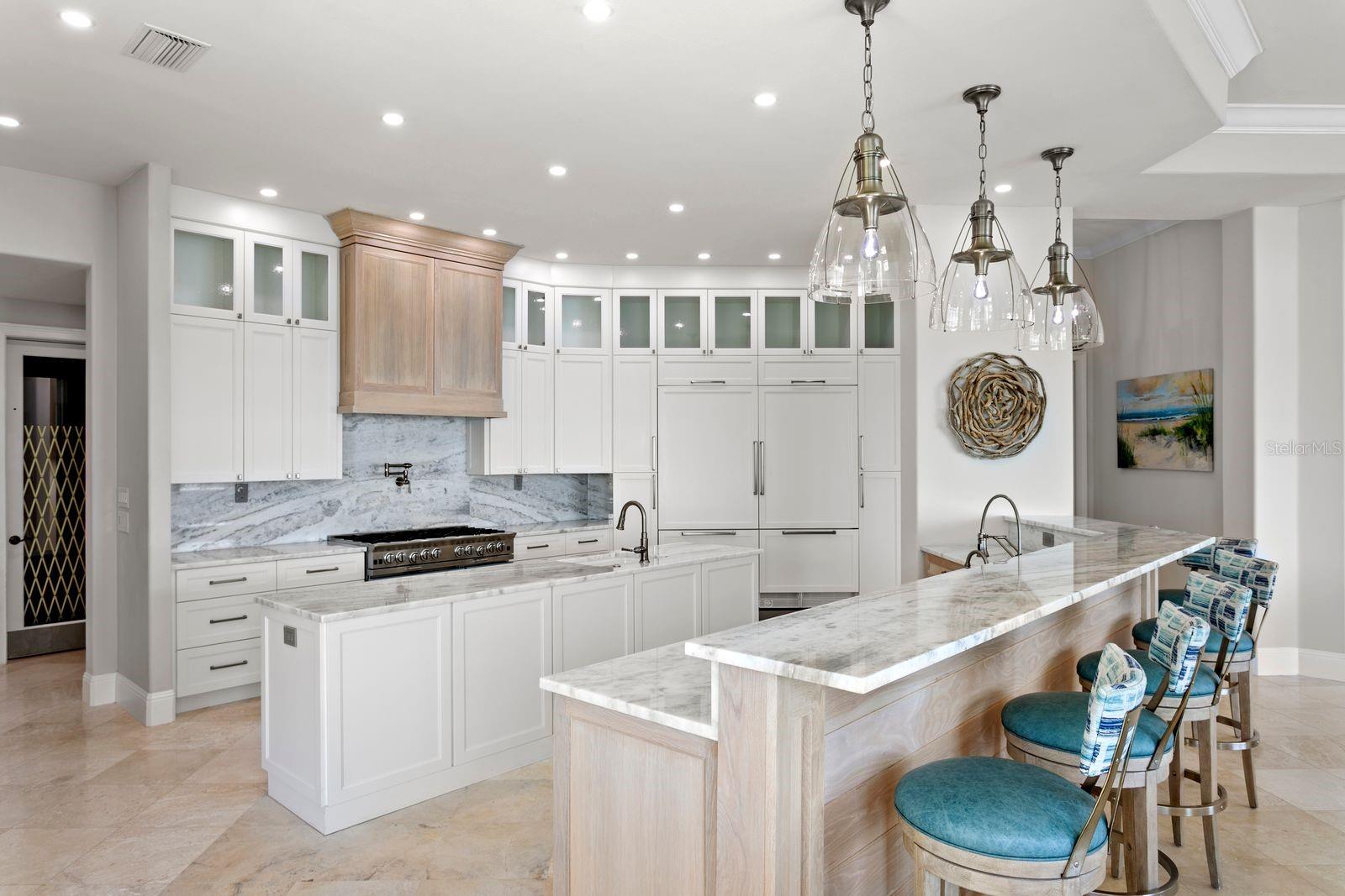 An elegant chef's kitchen appointed with quartz surfaces and statement designer lighting.