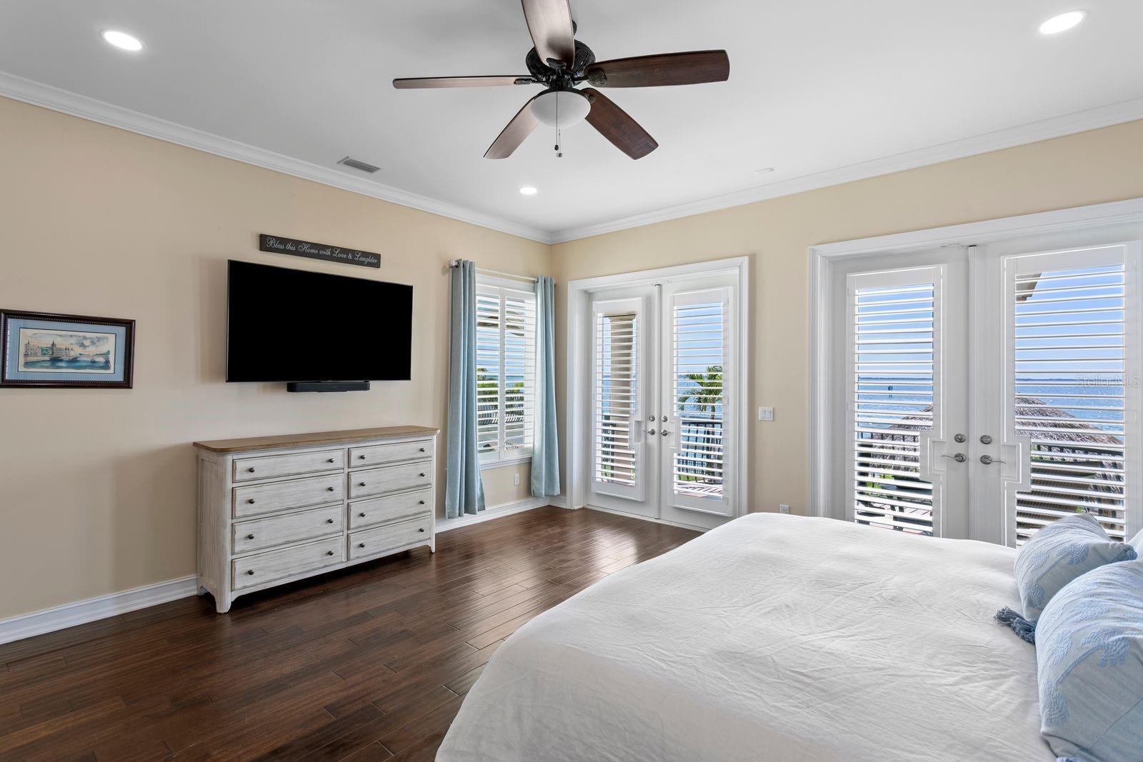 Another view of the main level, primary suite, highlighting the glass sliders, large balcony and views of Tampa Bay.