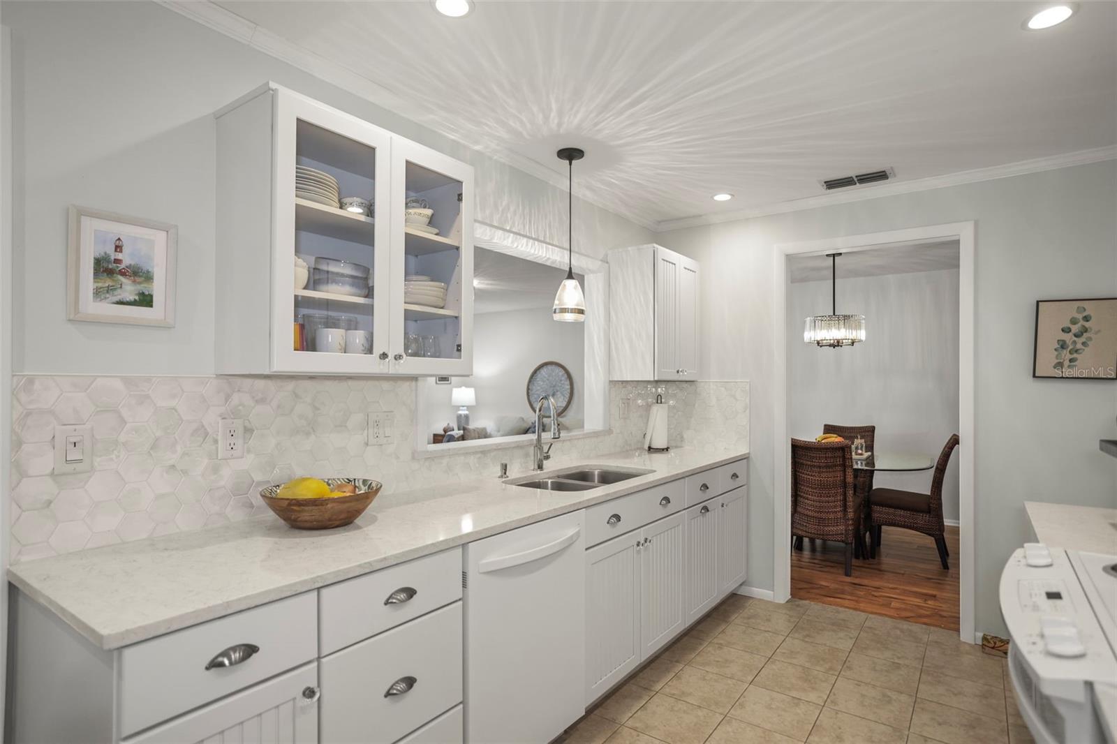 Kitchen with Solid surface counters, hardwood beadboard cabinetry, pretty glass tile backsplash, ceramic tile flooring and a pass through to the living room