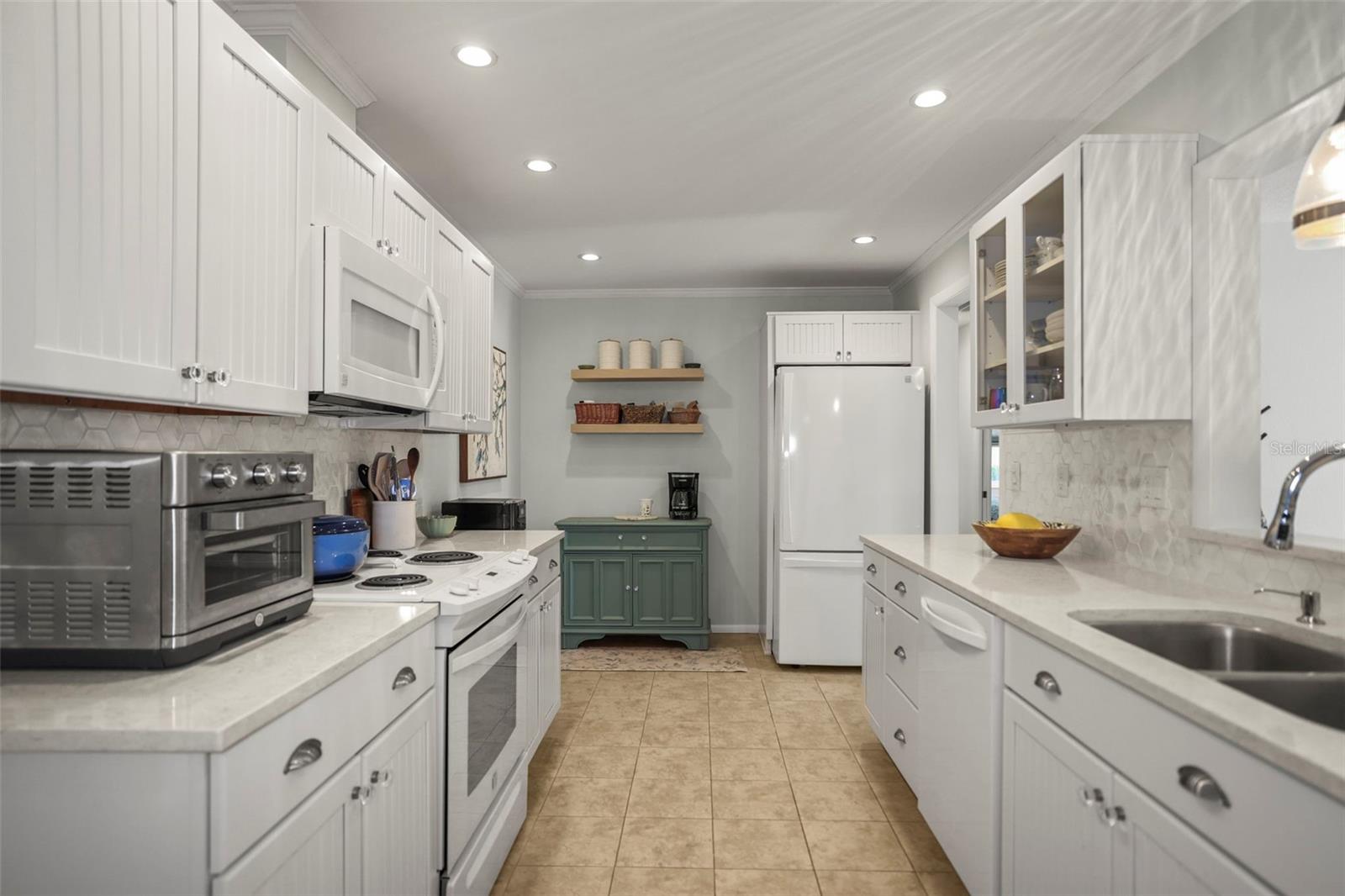 Kitchen with Solid surface counters, hardwood beadboard cabinetry, pretty glass tile backsplash, ceramic tile flooring and a pass through to the living room