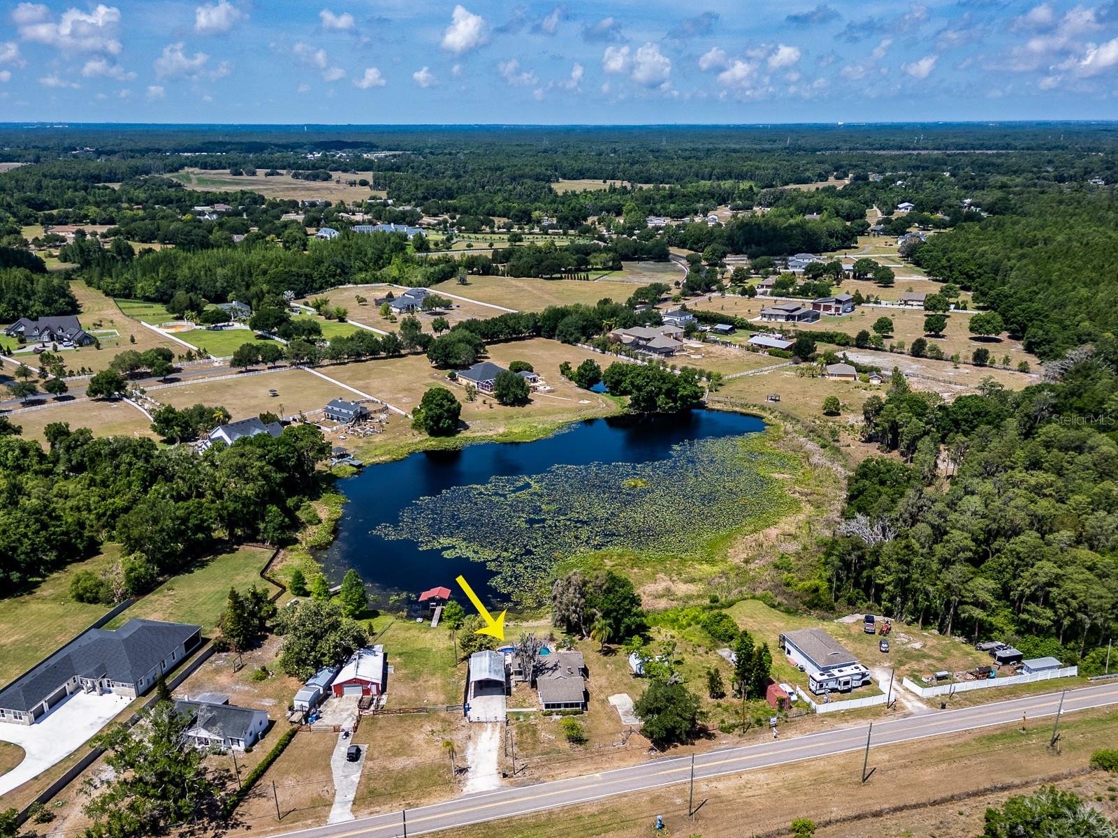 Aerial view of lakefront property with pool and surrounding land