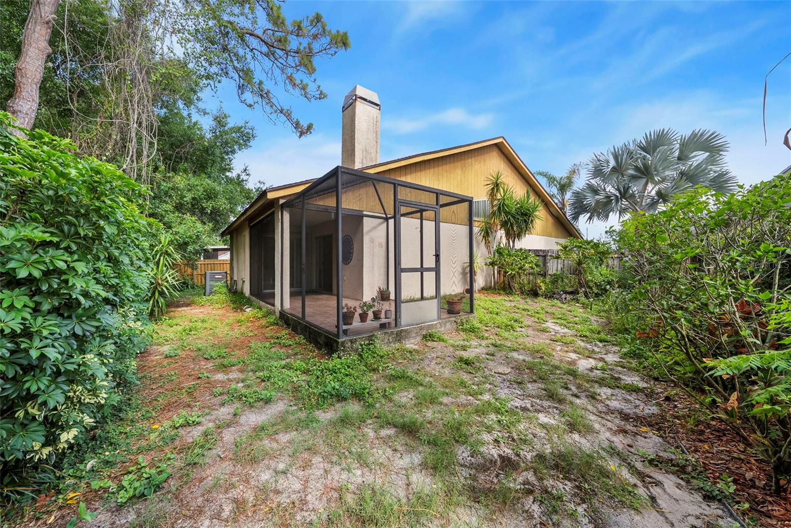 Rear exterior view with screened patio and mature landscaping.
