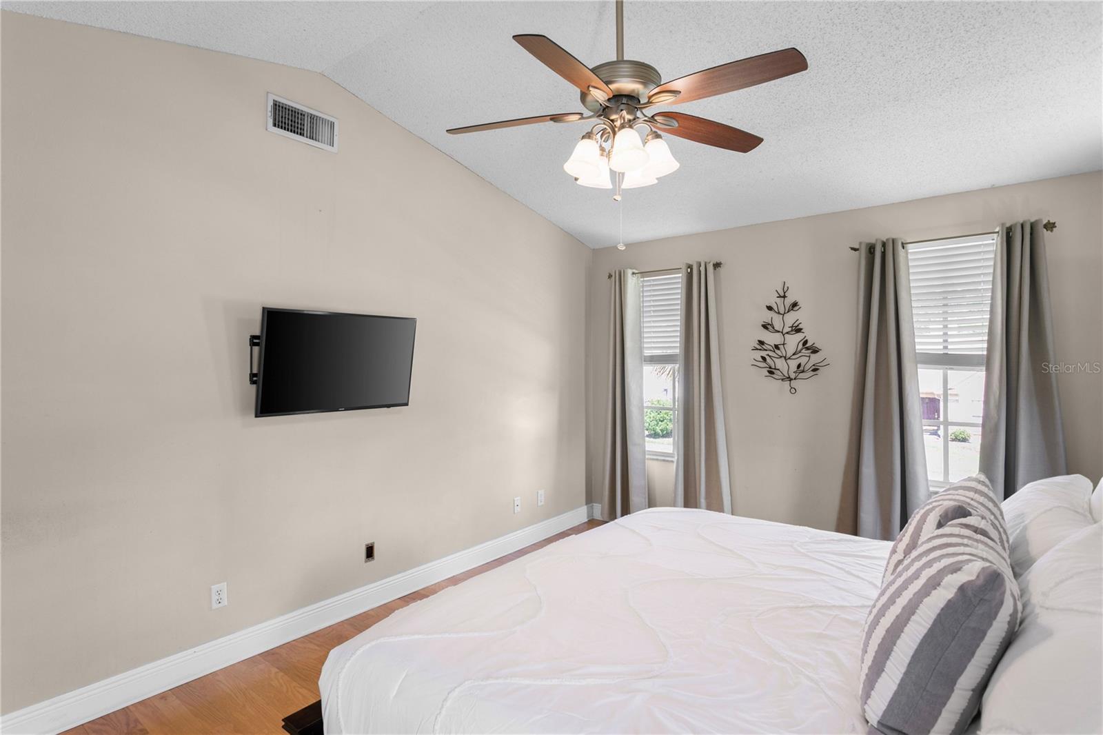 Large windows and ceiling fan in primary suite