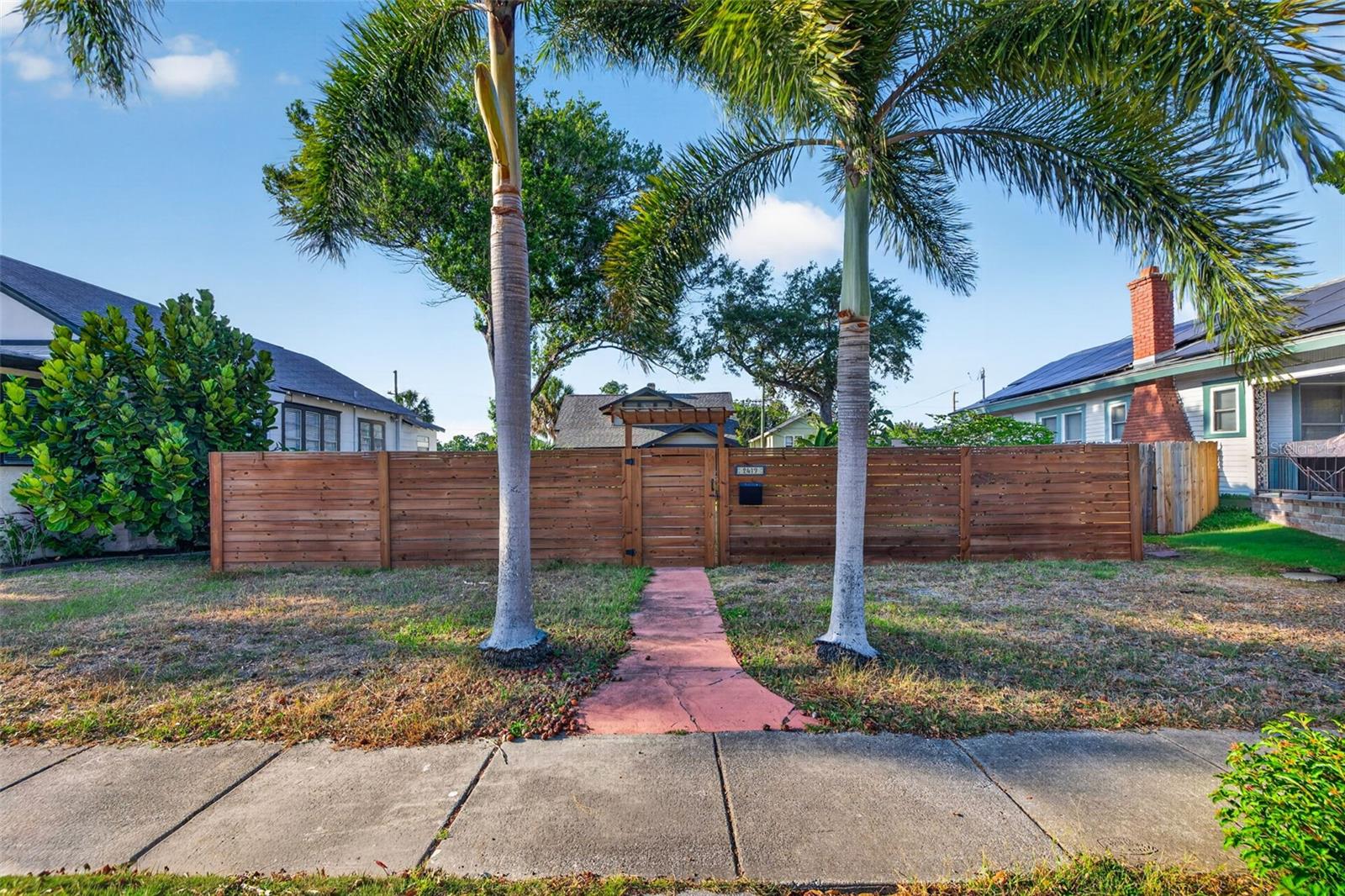 Prime curb appeal with established palms and a sturdy horizontal privacy fence enclosure.