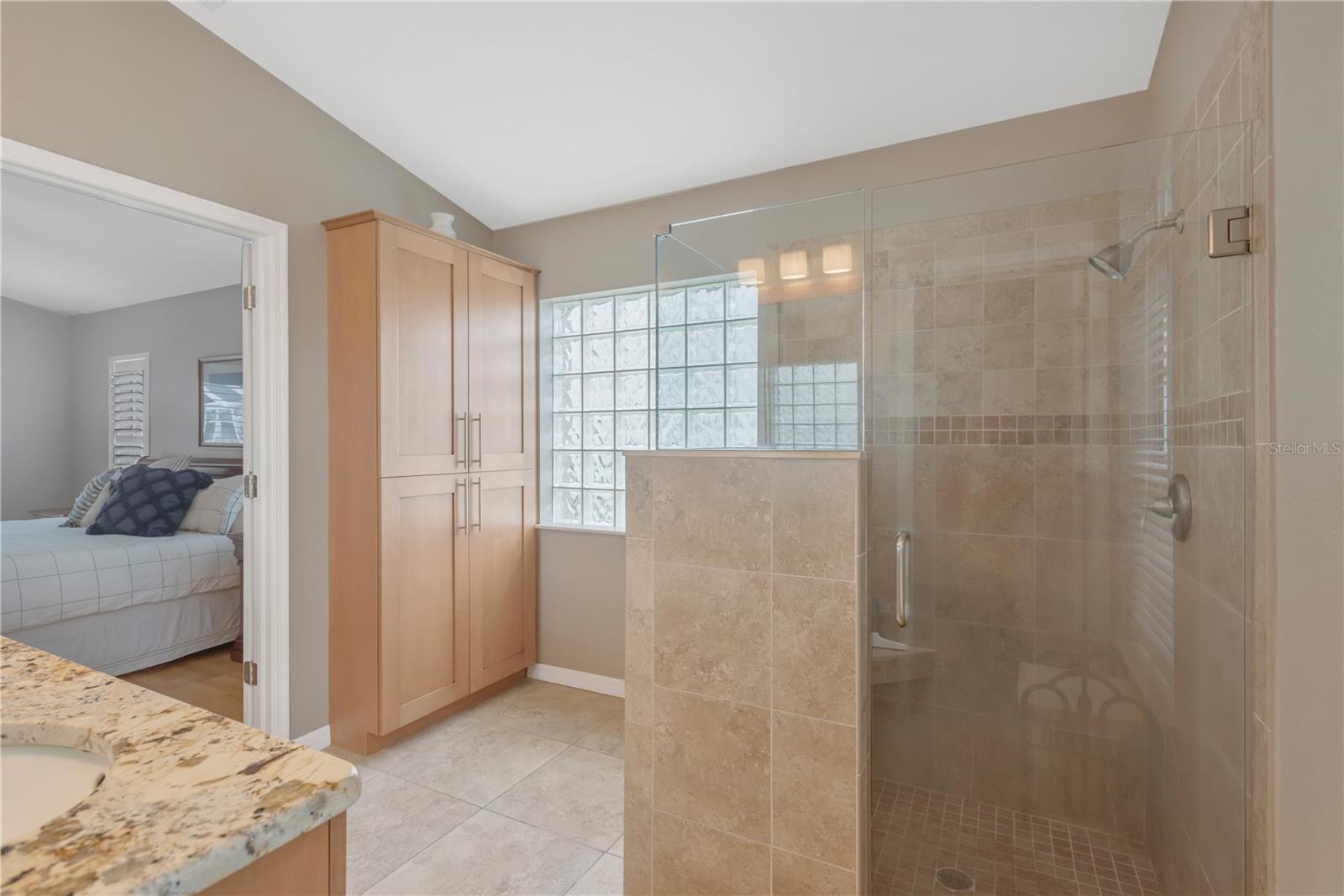 Buyers will enjoy the a large walk-in shower with built-in seating and seamless glass door and a custom built storage cabinet.