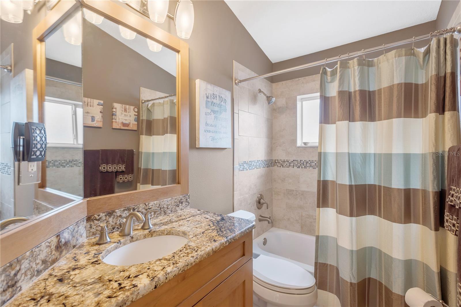 Updated guest bathroom off the family room/kitchen with custom cabinet, granite and a tub/shower with stunning tile surround.