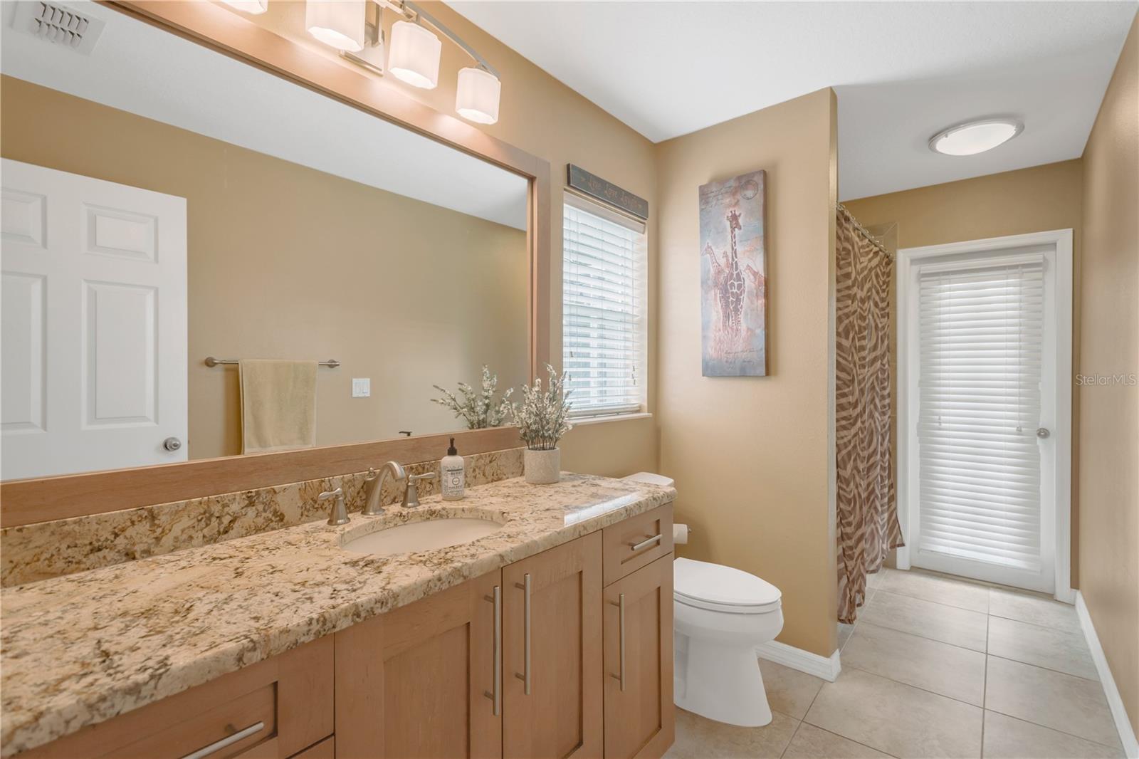 The full bathroom at the back of the home also serves as a pool bath with a single door to the pool deck and has custom cabinetry, granite counters and a tub/shower combination.