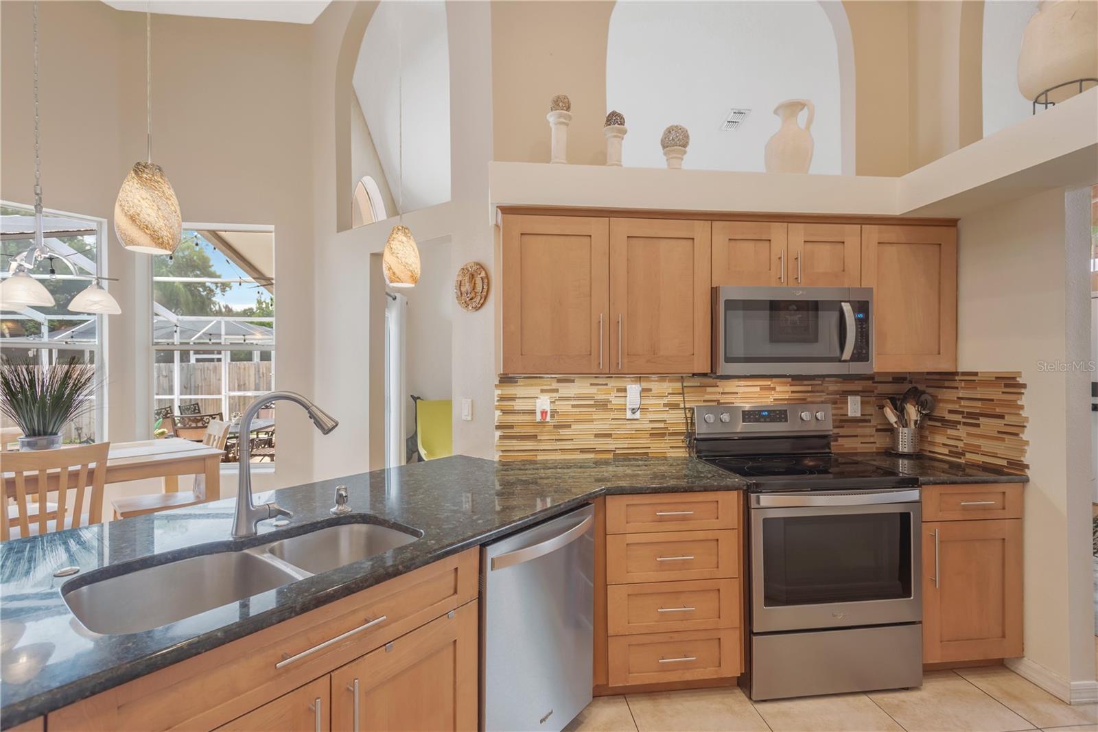The breakfast bar offers additional casual seating, while the granite countertops and stylish glass tile backsplash provide both elegance and easy maintenance.