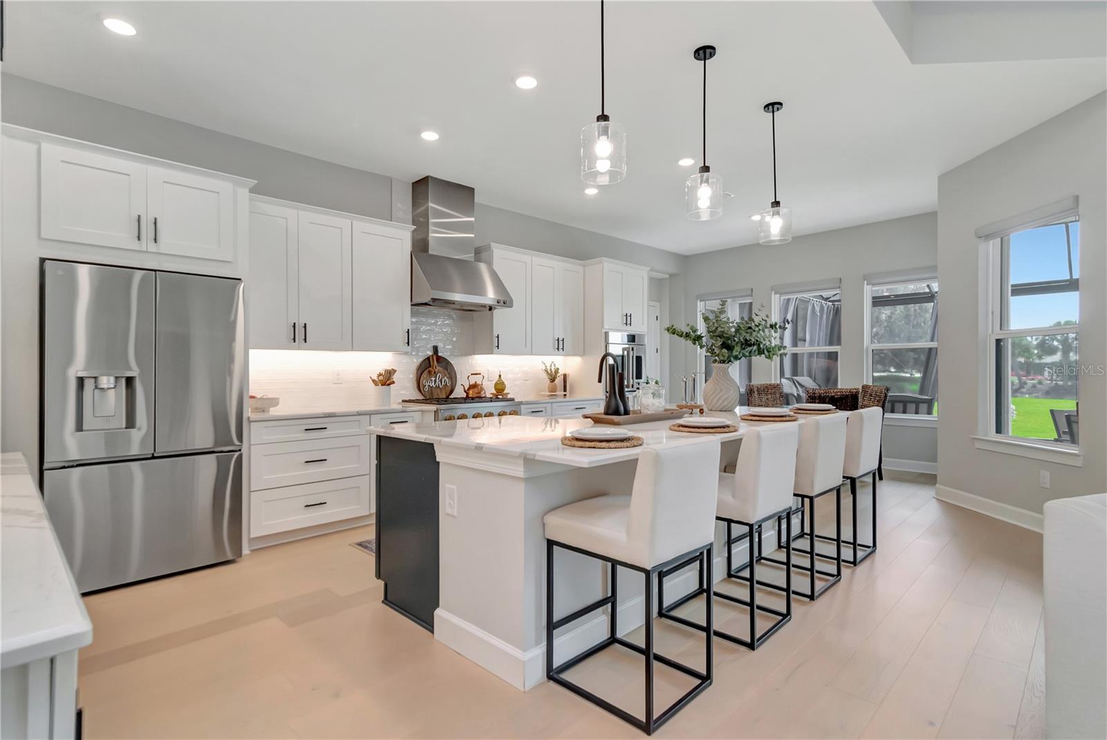 Gourmet Kitchen featuring Monogram luxury appliances, custom lighting, double ovens, expansive island AND a dry bar with full Butler's Pantry