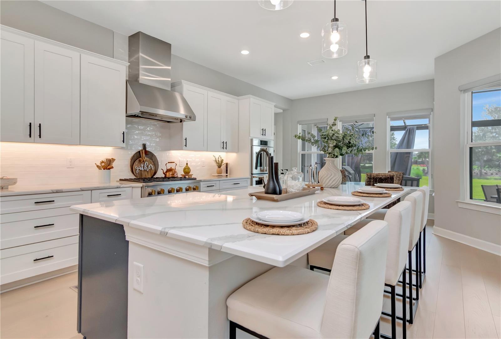 Gourmet Kitchen featuring Monogram luxury appliances, custom lighting, double ovens, expansive island AND a dry bar with full Butler's Pantry