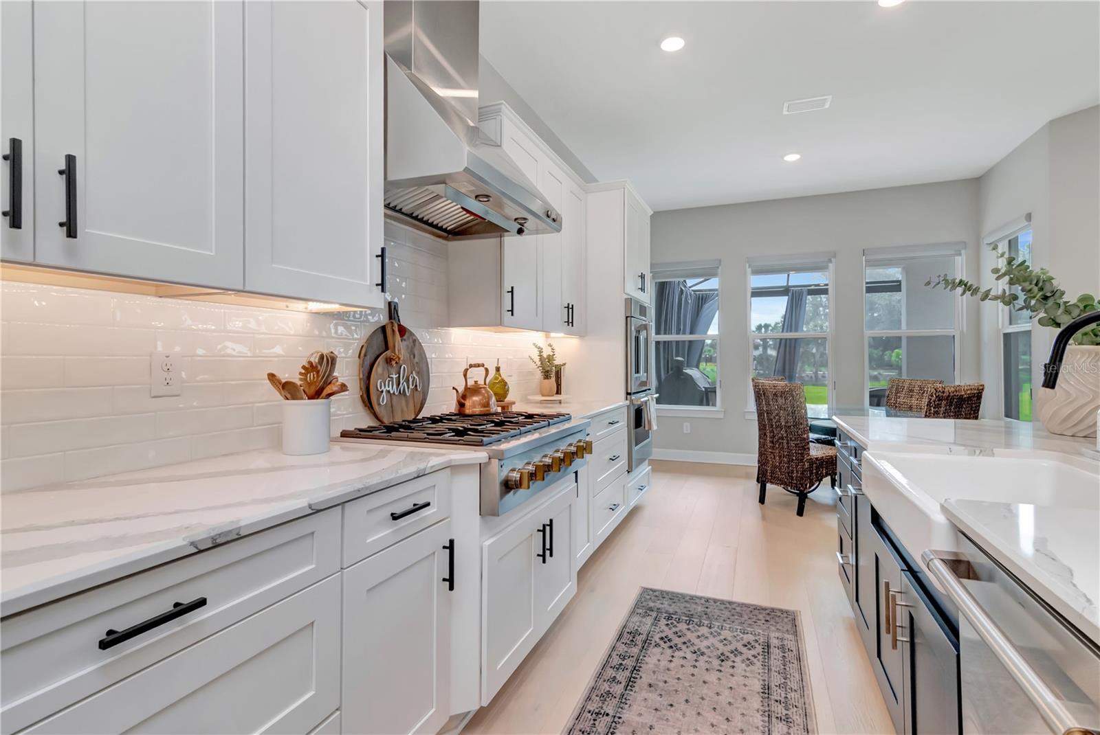 Gourmet Kitchen featuring Monogram luxury appliances, custom lighting, double ovens, expansive island AND a dry bar with full Butler's Pantry