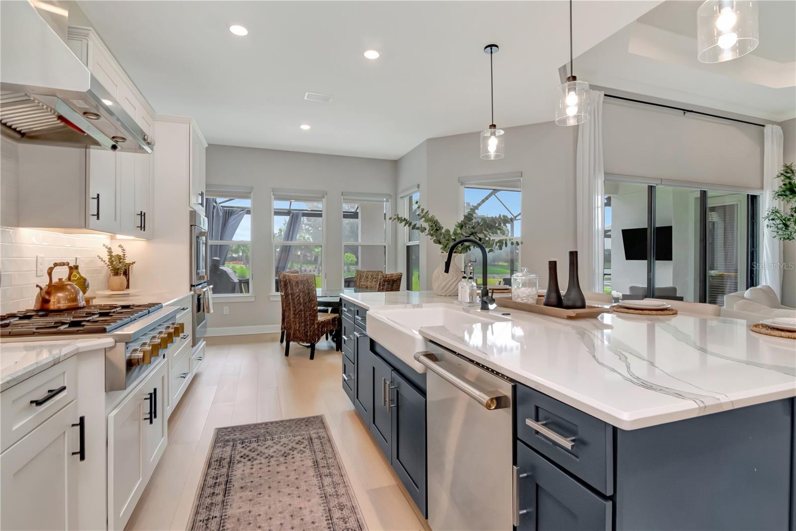 Gourmet Kitchen featuring Monogram luxury appliances, custom lighting, double ovens, expansive island AND a dry bar with full Butler's Pantry