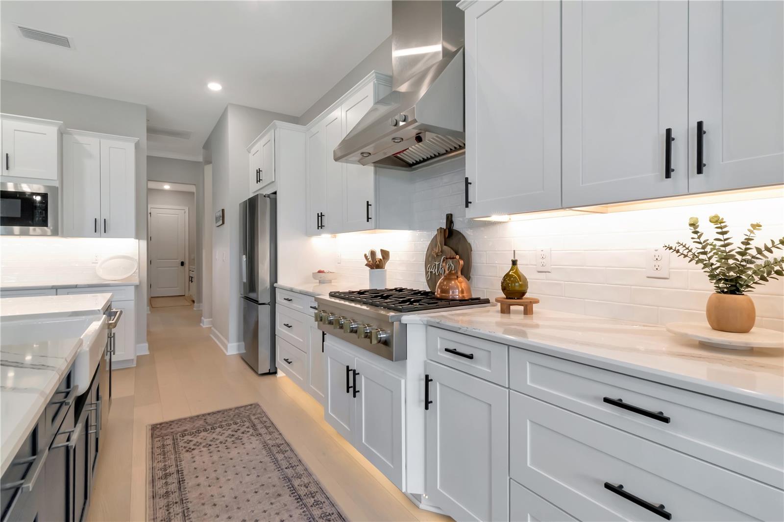 Gourmet Kitchen featuring Monogram luxury appliances, custom lighting, double ovens, expansive island AND a dry bar with full Butler's Pantry
