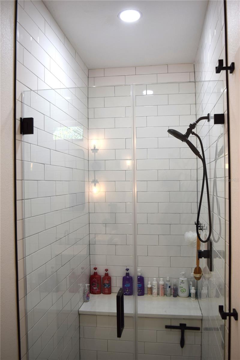 Walk-in Tile Shower has a full glass door and a convenient built in bench.