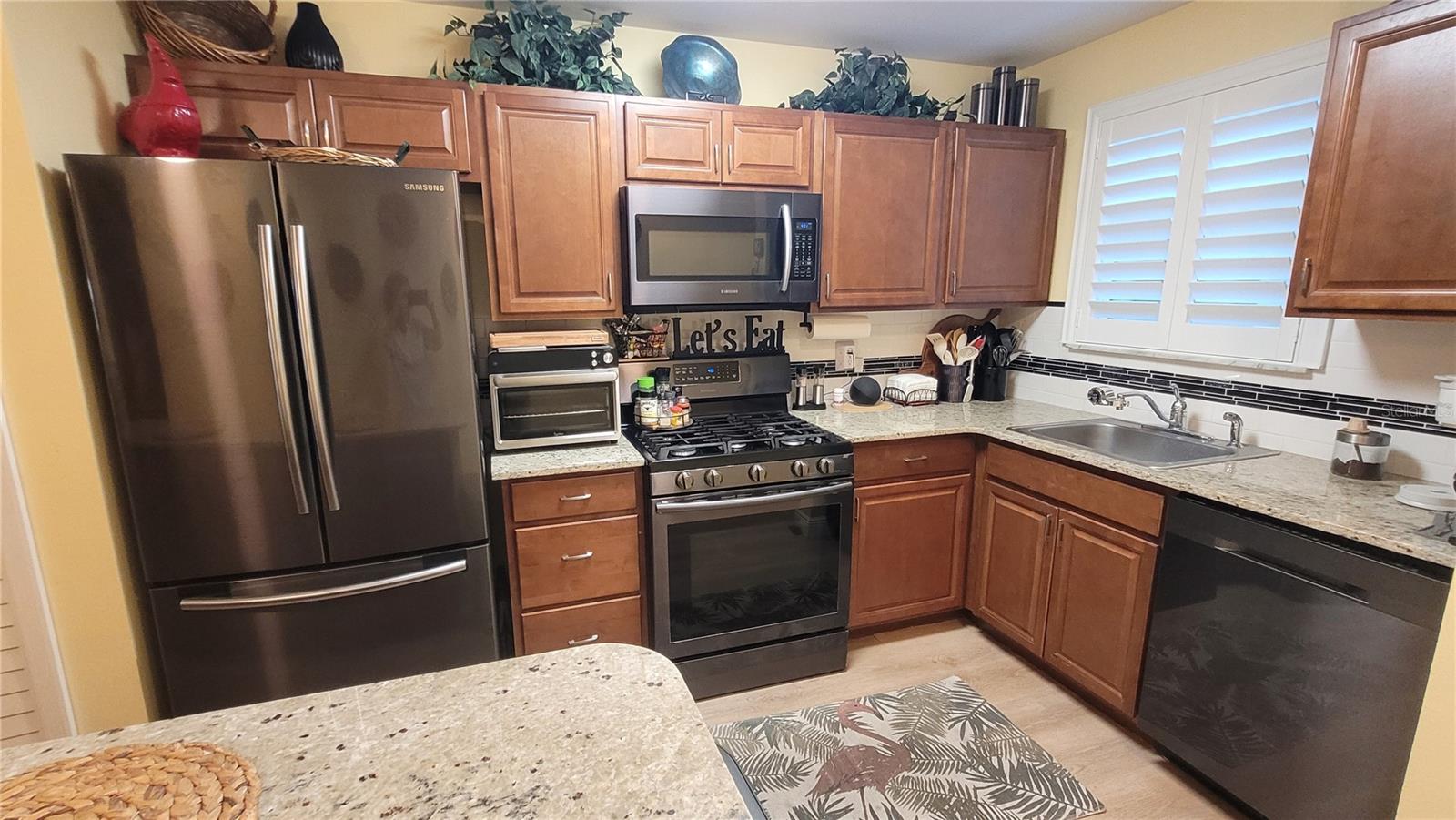 Bright kitchen has granite countertops and plantation shutters.