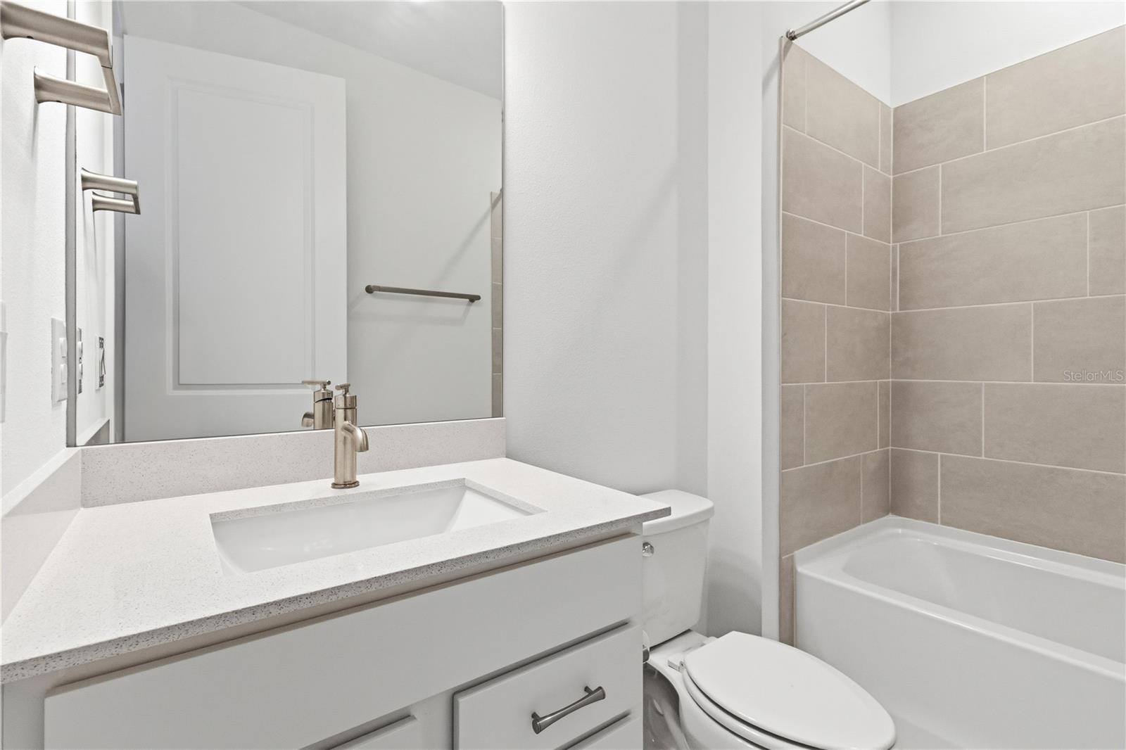 Fresh bathroom with upgraded finishes, bright cabinetry, and a tub/ shower.