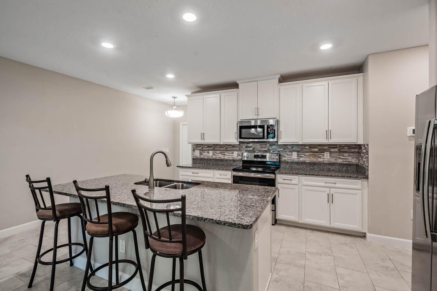 Kitchen w/granite counters & stylish backsplash
