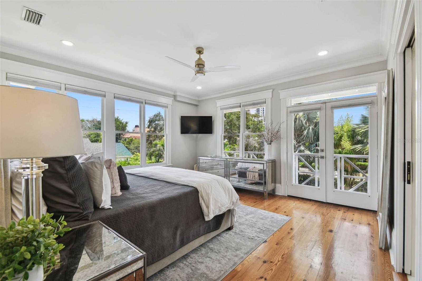 Primary bedroom overlooks the rear yard and pool area.  French doors lead to the balcony which wraps around to the entrances on the second floor of Guest Wing.  A lavish amount of natural light in this spacious room as you can see.