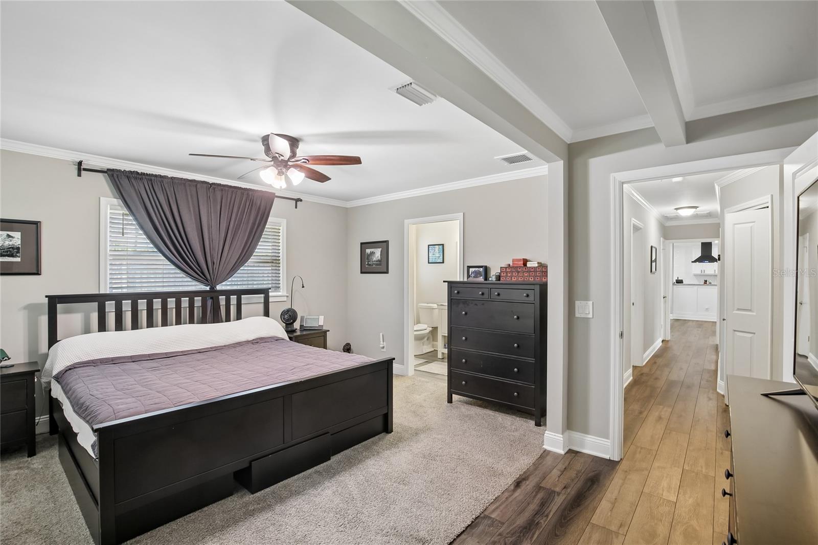 Primary Bedroom with En Suite Access – This primary suite includes direct access to the en suite bathroom and a smooth transition to the adjoining hallway. A mix of soft carpet and wood-look flooring adds definition to the space.