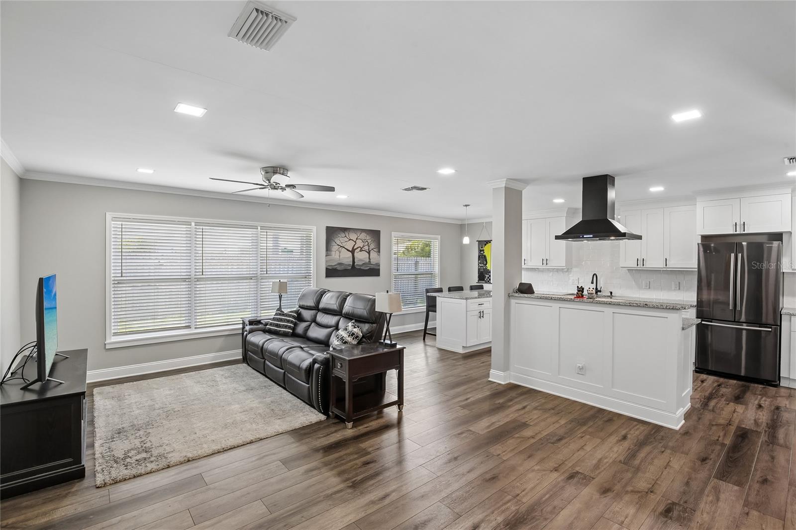 Open Living Area & Kitchen – This open-concept living space flows seamlessly into the updated kitchen, featuring wide-plank wood-look flooring, recessed lighting, and a bright, neutral palette. Large windows bring in natural light across the main gathering area.