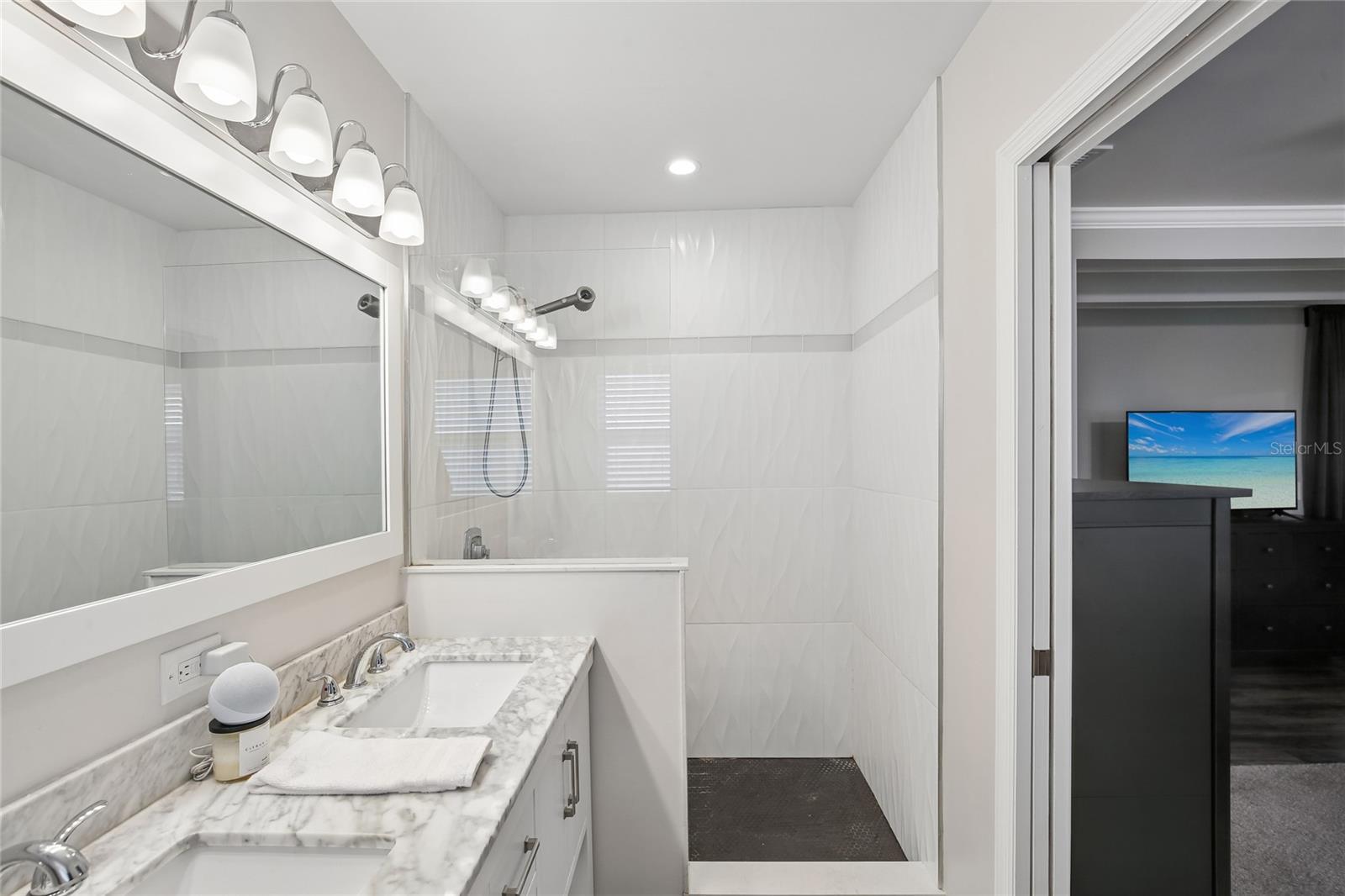 Primary En Suite Bathroom Shower View – This bath also includes a spacious walk-in shower with floor-to-ceiling tile and a sleek glass enclosure. The long vanity layout offers ample counter space and convenient everyday function.