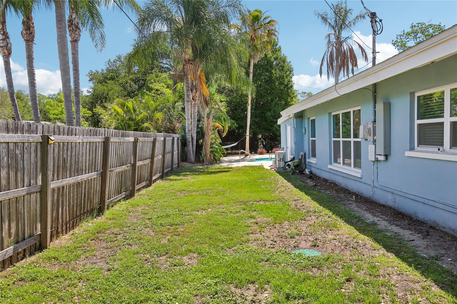 Side Yard & Rear Exterior – The side yard offers additional outdoor space along the rear of the home, with privacy fencing and a direct connection back toward the pool area. Mature landscaping and open lawn space add flexibility for outdoor use.