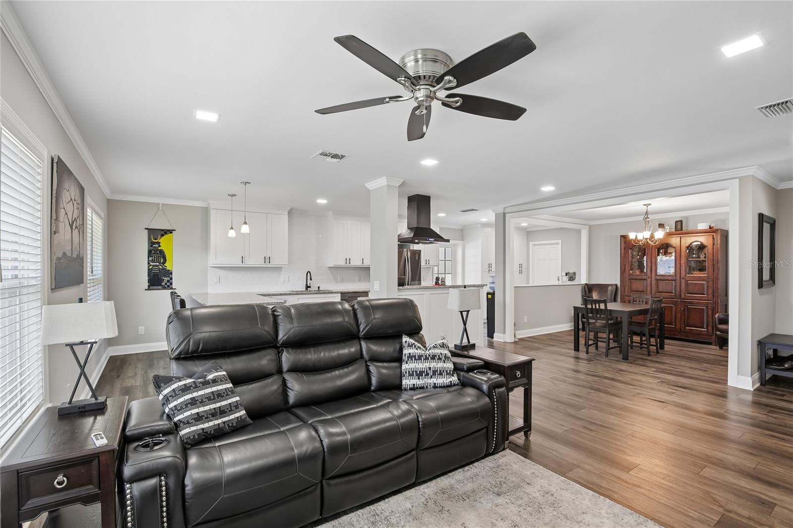 Living Room to Dining Area – A comfortable living area opens to the adjacent dining space and kitchen, creating an easy flow throughout the main living areas. Warm flooring and recessed lighting add a polished, cohesive feel.
