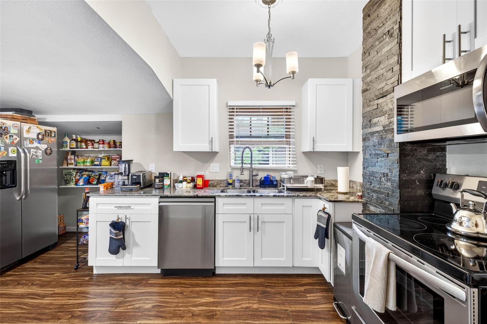 Kitchen fitted wiht stainless steel appliances, granite countertops, and dry bar with additional storage