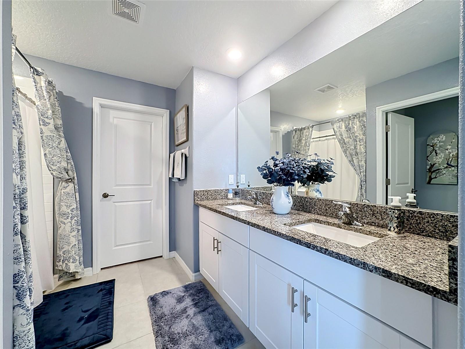 Primary en-suite bathroom with dual sink vanity and step-in shower