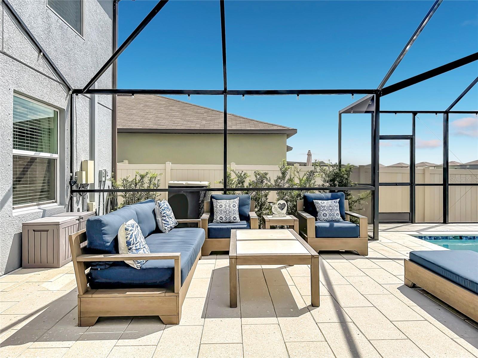 Backyard oasis featuring an enclosed heated saltwater pool and spa, expansive paver decking, and tranquil pond views