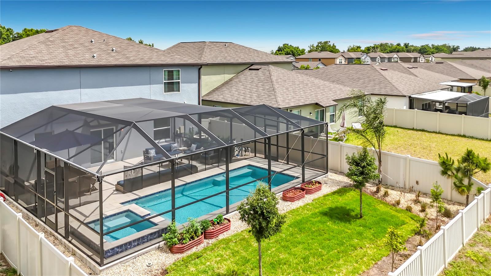 Backyard oasis featuring an enclosed heated saltwater pool and spa, expansive paver decking, and tranquil pond views