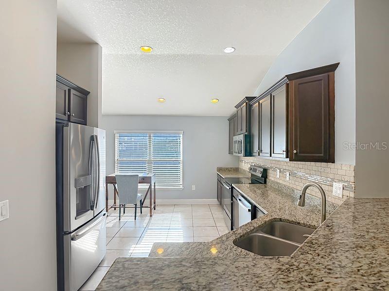 Spacious granite countertop bar area seamlessly overlooks the kitchen and opens to the living room, creating an inviting flow for entertaining and everyday living.