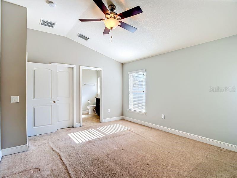 Spacious primary bedroom featuring vaulted ceilings, soft natural light, and neutral tones that create a relaxing retreat
