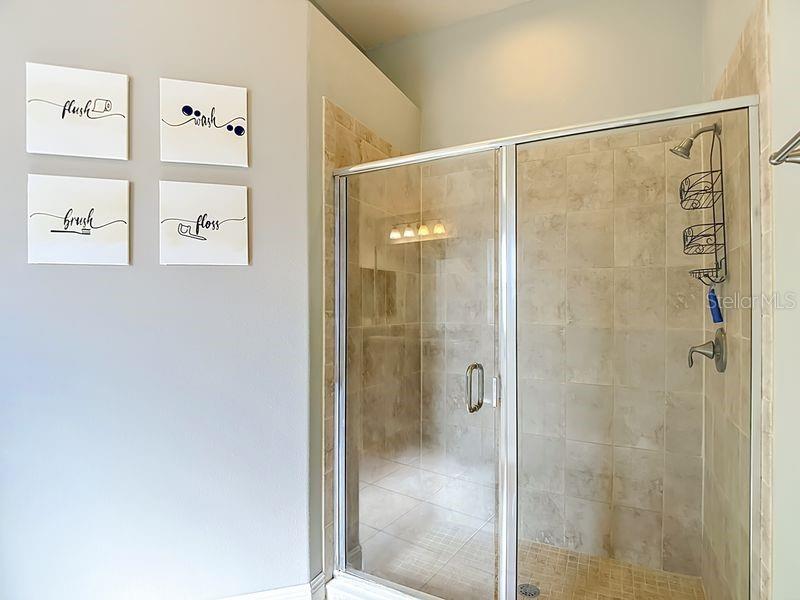 Primary bath has a spacious walk-in shower enclosed in glass