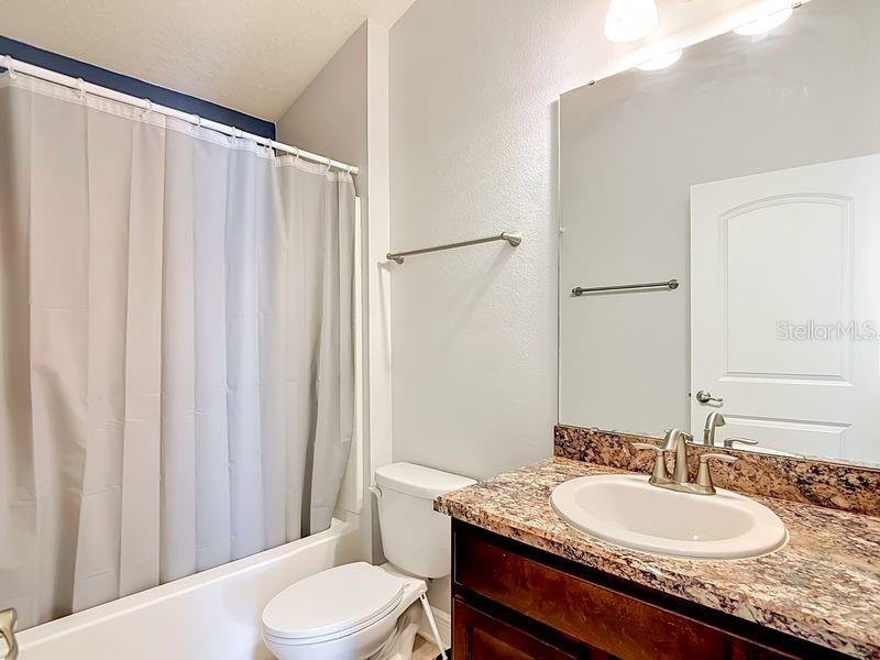 Well-appointed guest bathroom featuring luxury vinyl countertops, neutral tones and clean lines creating a fresh, inviting space for guests conveniently located between the guest bedrooms.