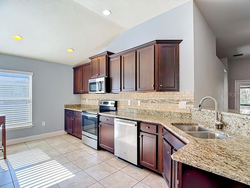 Beautifully updated kitchen featuring rich espresso cabinetry, granite countertops, and a coordinating tile backsplacsh.