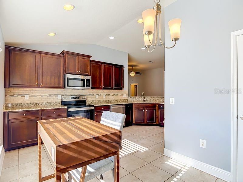 Cozy breakfast nook just off the kitchen, featuring tile floor and warm natural light. Perfect for casual dining, this space sits beside the pantry and offers a comfortable spot to enjoy morning coffee or family meals