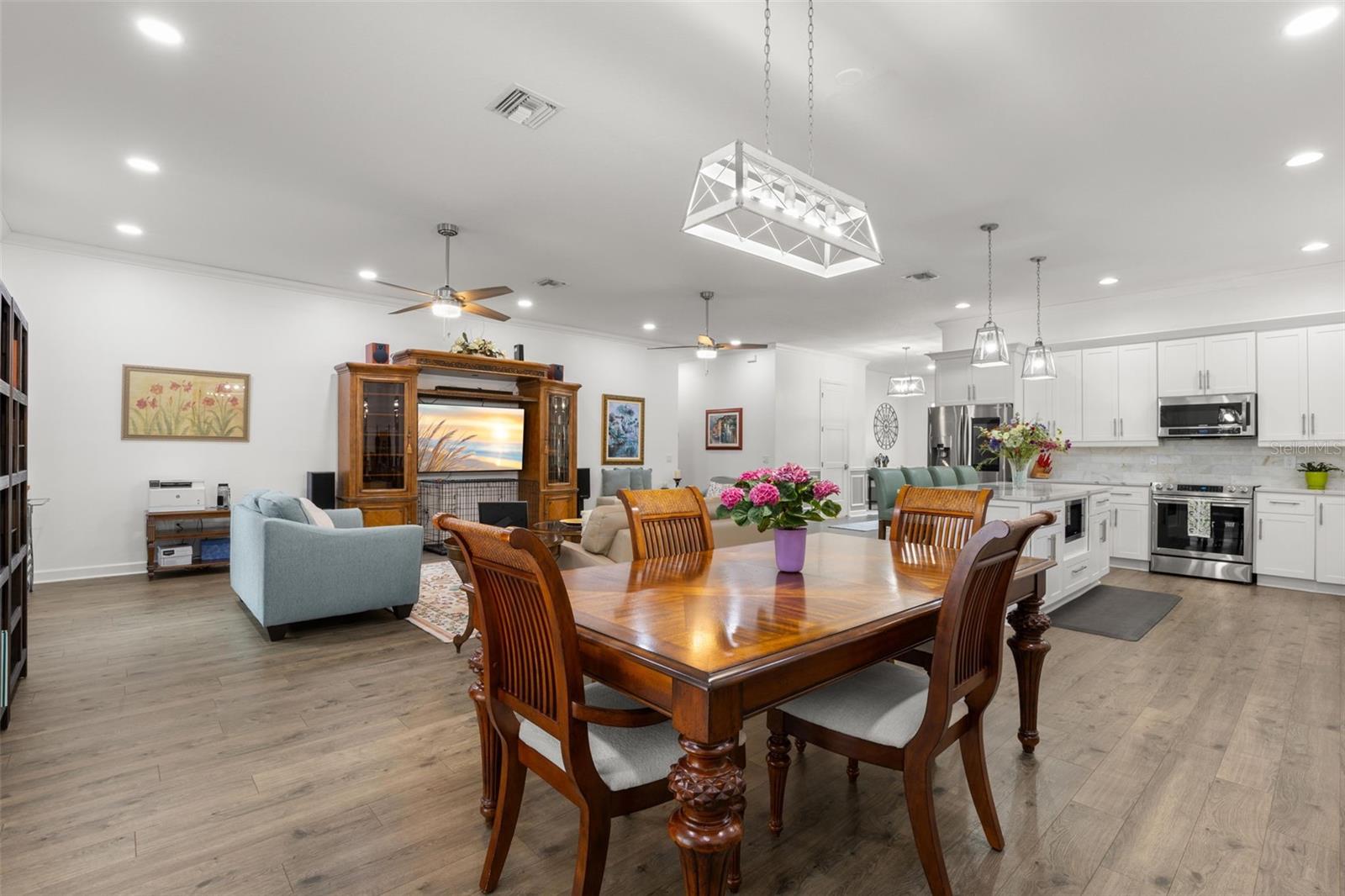 The spacious dining area flows effortlessly into the great room and kitchen, creating an open, cohesive layout enhanced by luxury vinyl flooring, recessed lighting, crown molding, and modern designer fixtures.