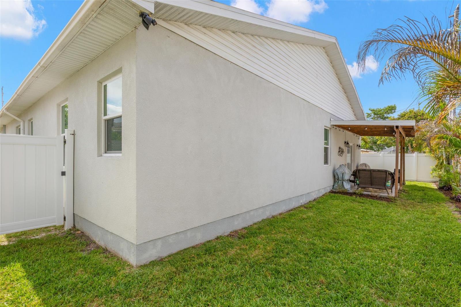 The fully fenced backyard offers privacy, low-maintenance landscaping, and ample green space surrounding the covered rear patio. Rain gutters, impact windows, and durable block construction contribute to the home’s thoughtful exterior design and functionality.