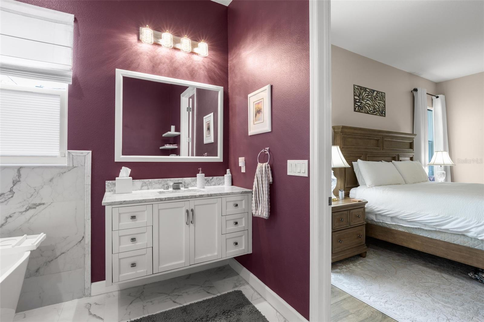 The beautifully appointed primary bath includes designer quartz countertops, upgraded shaker-style vanity cabinetry, contemporary lighting, upgraded plumbing fixtures, and dramatic marble-look tile flooring and wall accents. The spacious ensuite layout flows seamlessly from the primary bedroom, creating a refined private retreat.