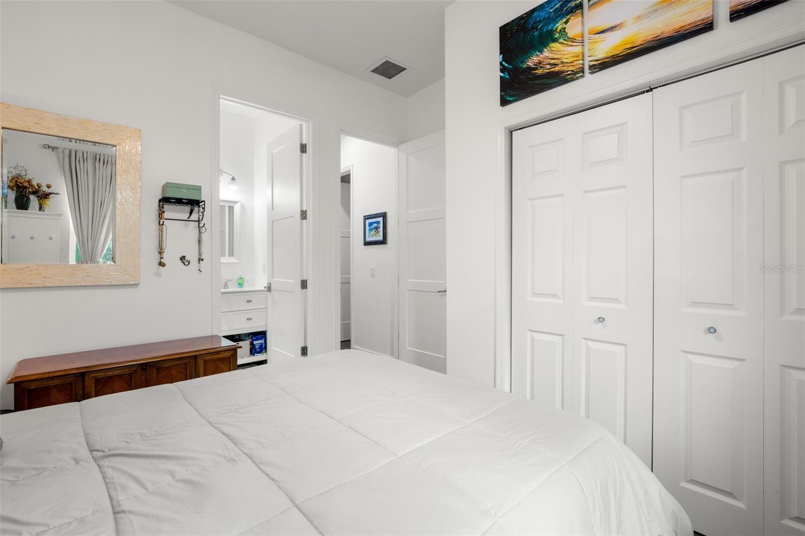 Bedroom 3 features wide-plank luxury vinyl flooring, abundant natural light, neutral finishes, a contemporary ceiling fan, and built-in shelving for additional display and storage space. The room also includes oversized paneled doors and convenient access to the ensuite full bath.