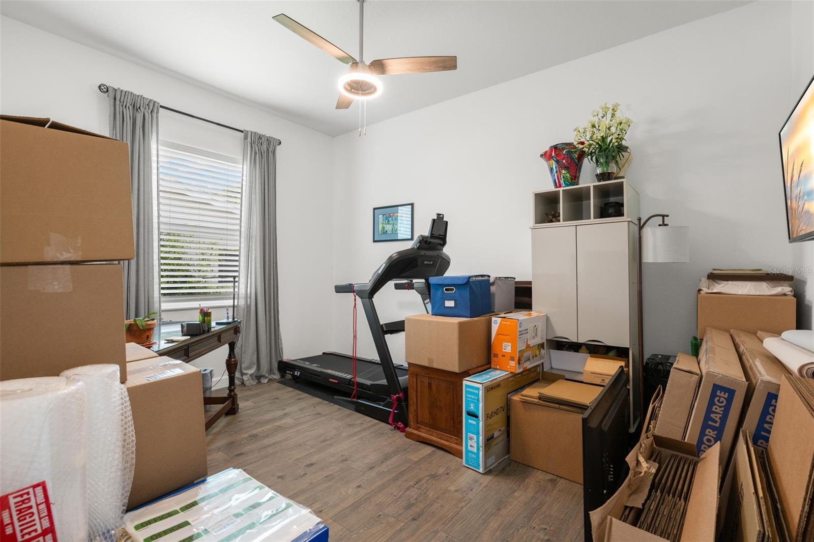 The flexible fourth bedroom or study includes wide-plank luxury vinyl flooring, a contemporary ceiling fan, abundant natural light, and a versatile layout adaptable for a home office, fitness room, or guest space.