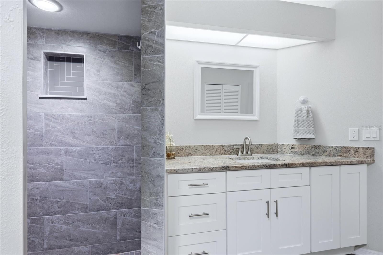PRIMARY EN-SUITE BATHROOM WITH SKYLIGHT, DUAL CLOSETS WALKIN AND BUILT IN, TALL VANITEIS AND GRANITE COUNTER TOP, WLAK IN SHOWER WITH HERRINGBONE TILE SHOWER FLOOR AND NICHE