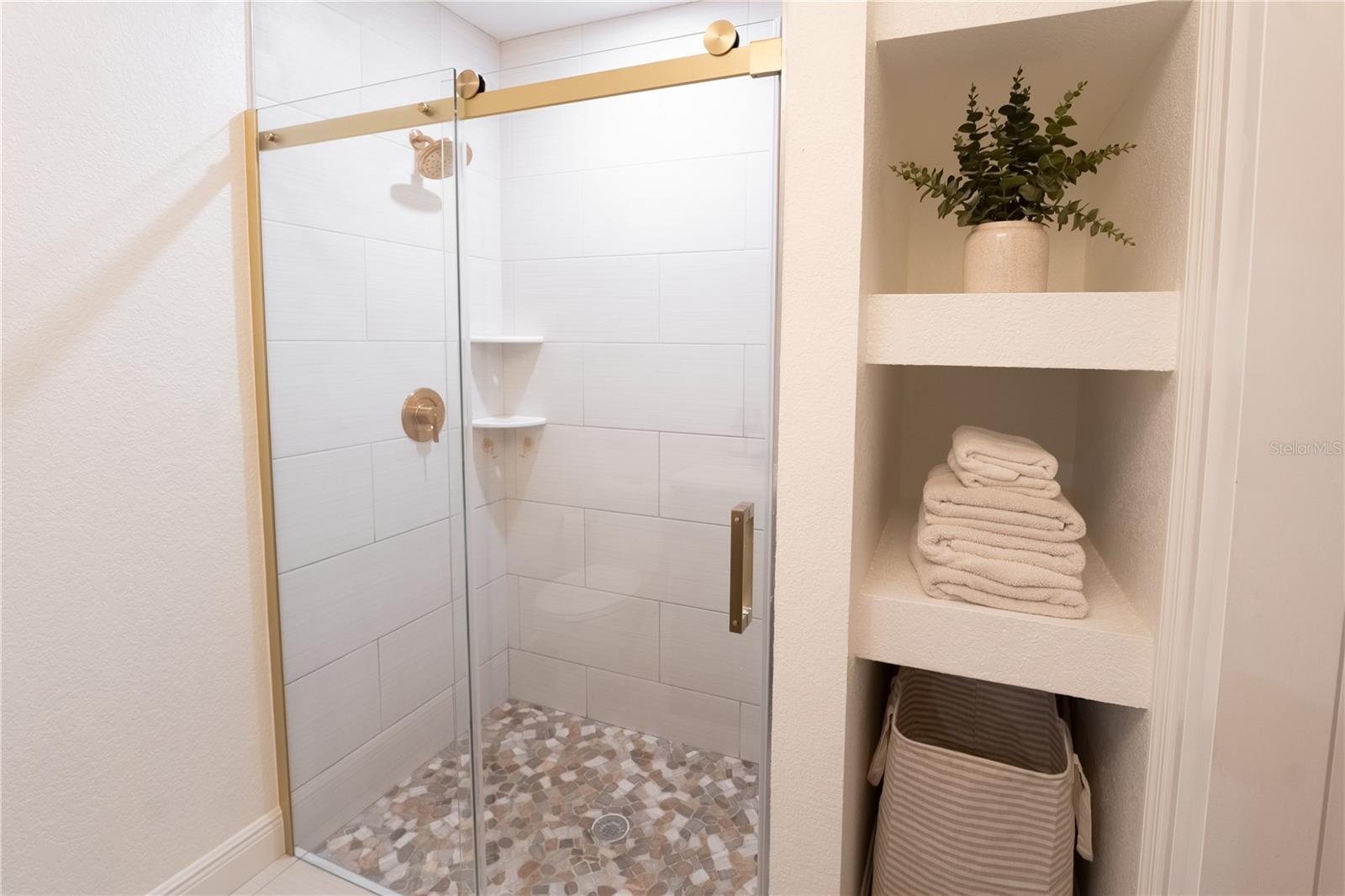 Tile walk-in shower and glass shower door with storage in primary bathroom