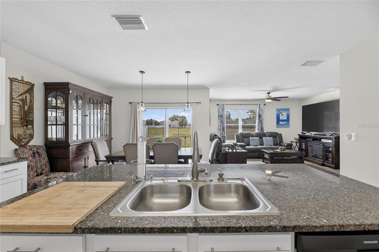 Open-concept kitchen, dining, and family room with seamless views of the covered lanai and peaceful pond backdrop.